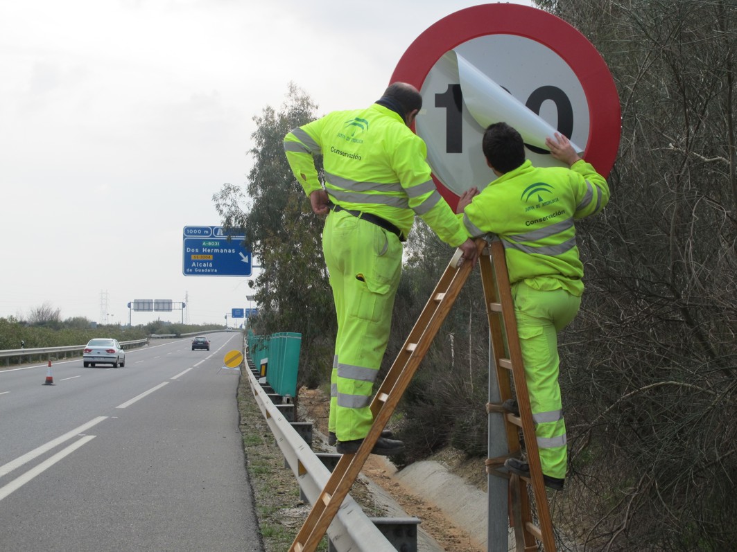 Operarios de los servicios de conservación cambian la información de la señal de límite de velocidad en la A-376 Sevilla - Utrera.